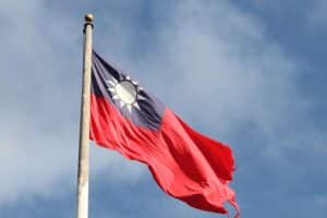 Taiwan-Flagge vor einem dramatischen militärischen Hintergrund, symbolisiert Spannungen zwischen Taiwan und China.