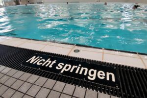 Kinder im Schwimmbecken, Eltern beaufsichtigen, Sicherheit durch Bronze-Pflicht für Schwimmausbildung.