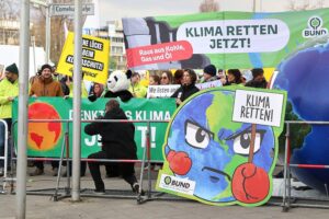 Demonstranten zeigen Transparente für Klimaschutz in einer lebhaften, engagierten Protestszene.