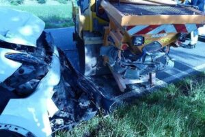 Ein Verkehrsunfall zwischen PKW und Asphaltwalze auf einer Landstraße mit Polizei vor Ort.