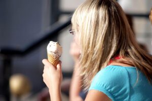 Frau genießt Eis in der Hitze, symbolisiert sommerliche Temperaturen und Hitzewarnung in Mecklenburg-Vorpommern.