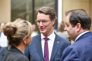 Drei Politiker stehen zusammen, bereit für wichtigen Austausch über europäische Wirtschaftschancen.