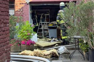 Feuerwehr löscht Garagenbrand im Hinterhof; zwei Verletzte, Feuerwehr unter Atemschutz im Einsatz.