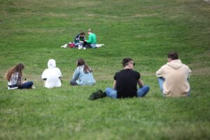 Junge Menschen genießen sonniges Wetter im Park während des warmen Juni in Bayern.