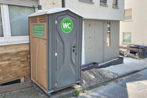 Mobile Toilettenkabine vor Neubau (Archiv) als Symbol für Städtebauförderung und kommunale Projekte.