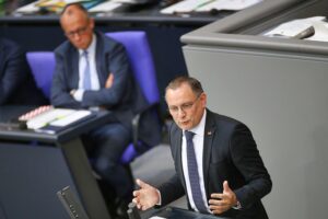 Friedrich Merz und Tino Chrupalla bei einer politischen Diskussion im Kontext der Umfrageergebnisse.