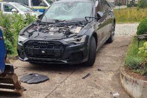 Zerstörter Audi A6 nach Explosion, Schäden an Haus und erheblichem Sachschaden sichtbar.