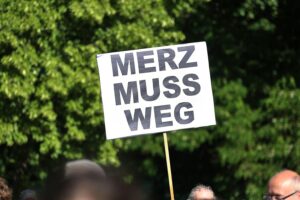Dresden, Demonstranten gegen Merz, Redner auf Bühne, politische Protestbewegung, öffentliche Unzufriedenheit.