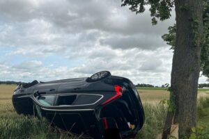 Verkehrsunfall mit umgekipptem Auto, Einsatzkräfte und beschädigtem Straßenbaum auf der L 411.