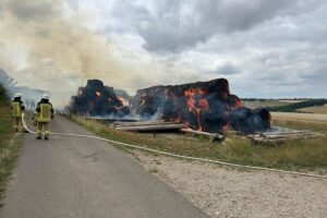 Heuballen brennen (Archiv), Feuerwehr löscht mehrere mutwillige Brände bei einem Sportplatz.