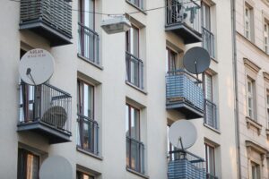 Satellitenschüssel an Wohnhaus, Symbol für moderne Kommunikation im sozialen Kontext.