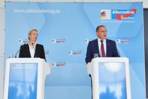Alice Weidel und Tino Chrupalla stehen zusammen, symbolisieren die AfD-Doppelspitze und deren Kontroversen.
