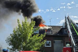 Mehrfamilienhaus-Dachstuhl steht in Vollbrand; Feuerwehr mit Drehleitern und Einsatzfahrzeugen in Recklinghausen.
