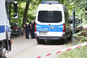 Polizeiwagen am Tatort nach CSD-Todesfahrt; Bundesinnenminister kritisiert Bewährungsstrafe des Attentäters.