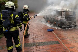 Feuerwehr löscht vollständig ausgebrannten VW-Bus in Debstedt mit Atemschutz und Einsatzkräften.