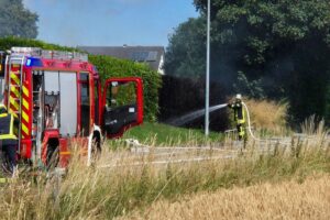 Feuerwehr löscht Heckenbrand, Sicherheitsmaßnahmen und Brandgefahr wegen trockener Witterung.