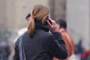 Frau telefoniert, ausdrucksstark, symbolisiert Diskussion über telefonische Krankschreibung und Gesundheitsreform.