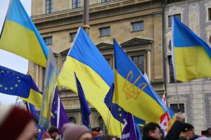 Pro-Ukraine-Demo mit Flaggen und Plakaten, die für Frieden und Unterstützung der Ukraine stehen.