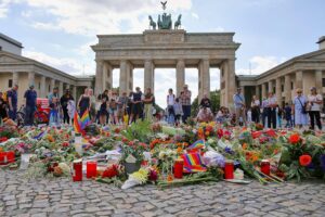 Trauernde Menschen nach CSD-Anschlag, Symbolbild für Debatte über Deradikalisierung und Demokratieförderung.