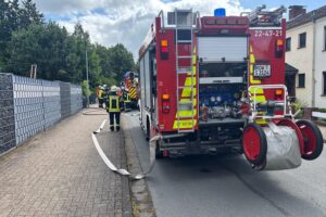 Feuerwehr im Einsatz bekämpft Brand in Schuppen, Rettungswagen steht bereit, Wärmebildkamera nutzt.