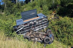 Schwerer Unfall auf der A1: Pkw mit Anhänger nach Überschlag, Dach in der Böschung, Feuerwehr im Einsatz.