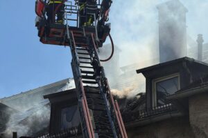 Feuerwehr im Einsatz, starke Rauchentwicklung, Menschenrettung, beschädigtes Wohngebäude nach Wohnungsbrand.