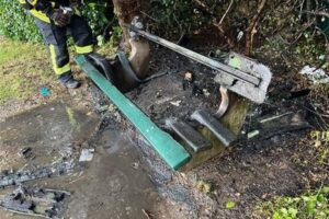 Beschädigte Sitzbank auf Spielplatz, Feuerwehr und Polizei ermitteln Brandursache.