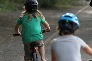 Kinder auf Fahrrädern im Straßenverkehr; Studie zeigt unsichere Fähigkeiten wie Schulterblick und Handzeichen.