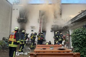 Feuerwehr im Einsatz bei Wohnungsbrand: dichter schwarzer Rauch aus Hinterhofgebäude-Fenstern in Dortmund.