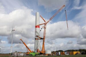 Archivfoto: Windrad-Bau mit Arbeitern am Fundament, im Hintergrund weiteres Windrad für Klimaschutz-Investitionen.