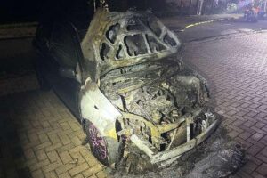 Zerstörter Toyota bei PKW-Brand in Spieka-Neufeld, Polizei und Feuerwehr im Hintergrund (Archivfoto).