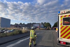 Feuerwehr im Einsatz bei Brand in Industriehalle, Rauchentwicklung, Einsatzkräfte, Rettungswagen und verletzt vier Personen.