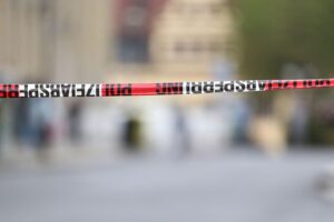 Polizeiabsperrung mit Einsatzfahrzeugen und evakuierten Menschen im Hintergrund, Sicherheitsmaßnahmen deutlich sichtbar.