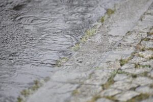 Regenwetter-Archivbild: grauer Himmel, Regenstreifen und nasse Straße, später mögliche Gewitter mit Starkregen.