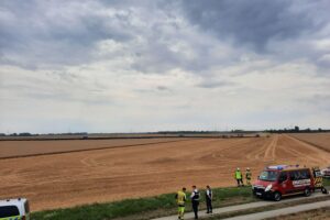 Feuerwehr und Polizei an einer Einsatzstelle nach Flächenbrand: brennendes Getreidefeld, links Einsatzwagen, Löschmaßnahmen.