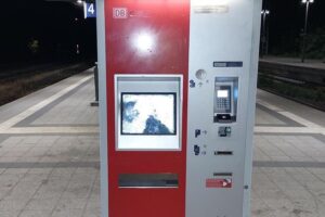 Beschädigter Fahrkartenautomat im Hauptbahnhof Neustrelitz, dazu Polizei/Archivfoto.