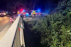 Unfall in Paderborn-Wewer: verunfallter Pkw tief in die ehemalige Almetalbahn gestürzt, Rettungskräfte im Einsatz.