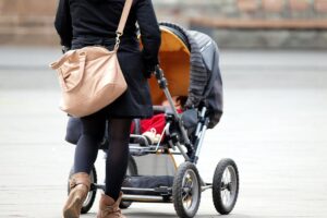 Mutter mit Kleinkind und Kinderwagen im Archiv, UNICEF und WHO fordern bessere Stillunterstützung.
